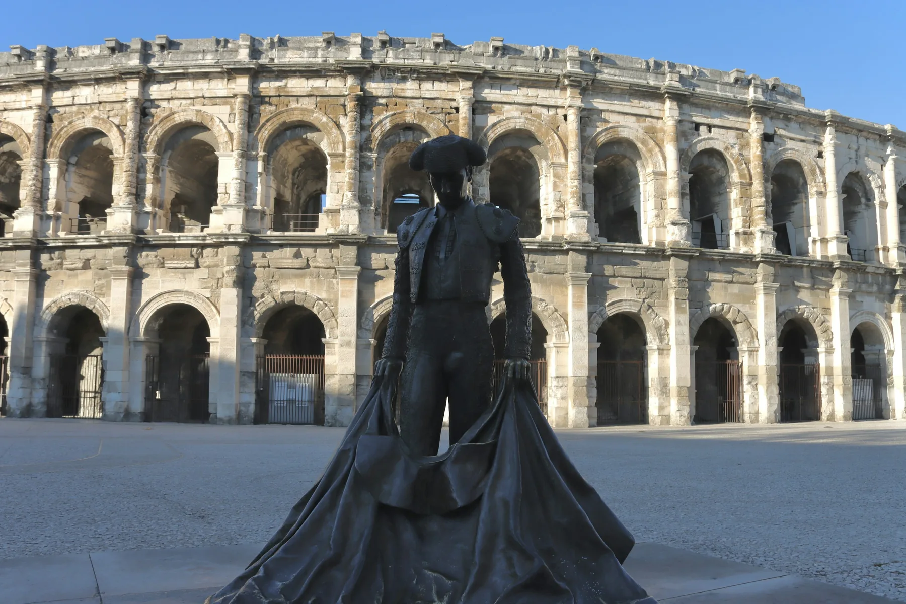Les Arènes de Nîmes et, devant, la statue de Nimeño II