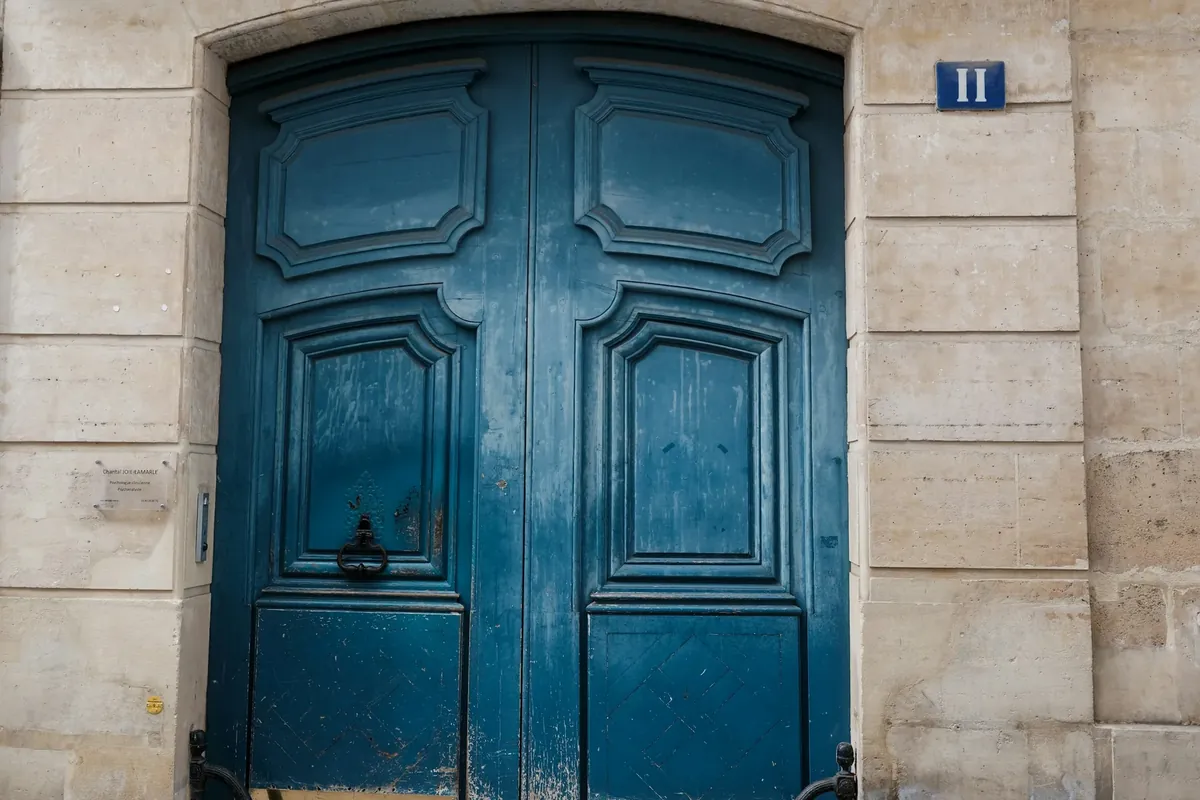 Une porte d’entrée en bois bleu dans une façade de pierre